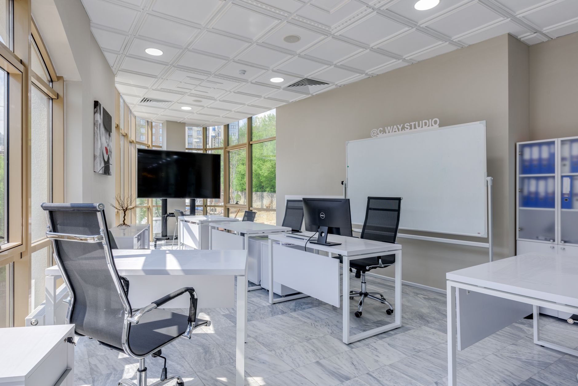 Bright workroom with desks, a screen and a whiteboard